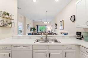 A modern kitchen with white cabinetry, a double sink, and a built-in dishwasher. - Vacation Dreams at Bahama Bay (Davenport)