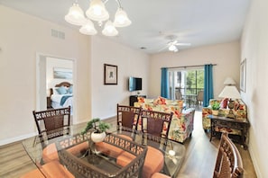 A living room with a glass dining table, wicker chairs, a sofa with a floral pattern, a ceiling fan, and a television. - Vacation Dreams at Bahama Bay (Davenport)