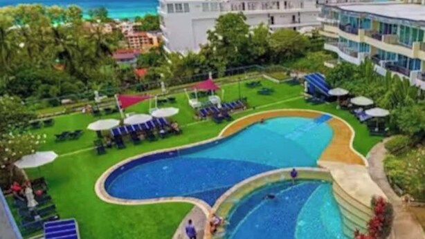 A resort with a large pool, lounge chairs, and a view of the ocean. - Sunset View Condo Steps from Karon Beach #C162 (Tambon Karon)
