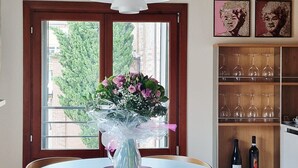 Et spiseområde med et rundt bord, stole, en vase med blomster og et vinskab.