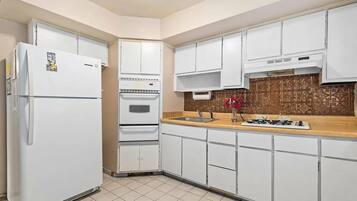 A kitchen with white cabinets, a refrigerator, an oven, a sink, and a stove.