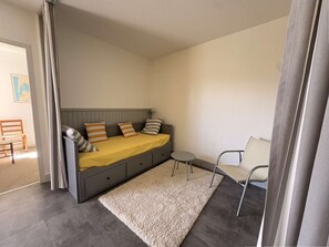 Ein kleiner, moderner Raum mit einem Bett, einem Tisch, einem Stuhl und einem Teppich.