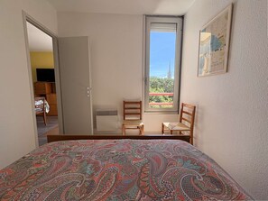 Ein Schlafzimmer mit Bett, Fenster mit Aussicht, Stuhl und Schreibtisch.