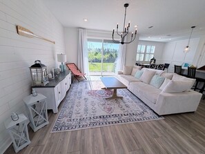 Ein modernes Wohnzimmer mit einer Couch, einem Couchtisch und Blick ins Freie.