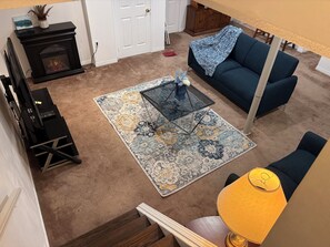 A living room with a fireplace, sofa, coffee table, and a lamp.