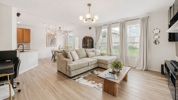 Een moderne woonkamer met een hoekbank, een salontafel en een eethoek met een tafel en stoelen.