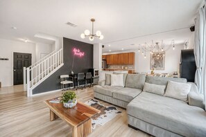 A modern living room with a sofa, coffee table, and a staircase. - NEW Stylish 3BR by Tesla, Airport + F1 (Del valle)