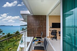 Ein moderner Balkon mit Meerblick, ein Essbereich mit Stühlen und Tisch sowie ein Zimmer mit Fernseher und Schreibtisch.