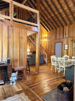 Ein rustikales Holz-Interieur mit Schlafgalerie, Küche, Essbereich und einer Treppe.