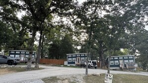 A campground with mobile homes, a gravel path, and trees. - Freedom-Cabin-1 @ Eagle Hollow (Goreville)