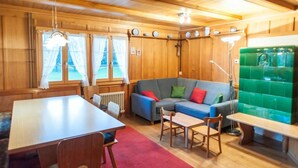 Een gezellige kamer met houten inrichting, een bank, een eettafel en een bankje.