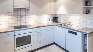 Een moderne keuken met witte kasten, een inbouwoven, een koffiezetapparaat en een vaatwasser.