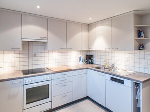 A modern kitchen with white cabinets, a built-in oven, a coffee maker, and a dishwasher. - Vacation home Lorenz by Interhome (Flüeli-Ranft)