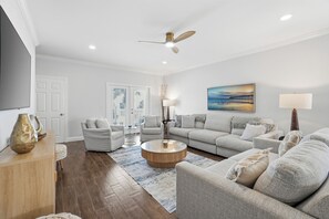 A living room with a sofa, armchairs, a coffee table, and a TV. - Luxe Beach Retreat | Pool • Arcade • Walk to Beach (Jacksonville Beach)
