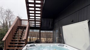 Un jacuzzi con terraza de madera y una escalera que lleva a un espacio cubierto.