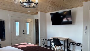 Habitación de hotel con cama, escritorio, silla, televisor y ventilador de techo.