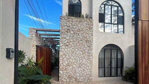 Un edificio moderno con fachada de piedra, camino de grava y puerta de madera.