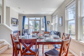 Un comedor con mesa de vidrio, sillas de madera y vistas al exterior.