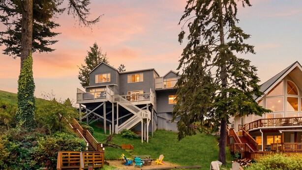 Une propriété au bord du lac, dotée d’un quai en bois, d’une terrasse couverte et d’une maison avec une grande fenêtre donnant sur l’eau.