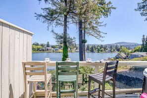 A balcony with two chairs and a table, overlooking a lake with houses and trees in the background.