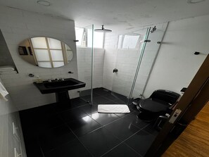 Une salle de bain moderne avec un lavabo noir, une douche en verre et des toilettes.