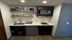A compact kitchen with a sink, stove, microwave, and storage cabinets. - Lourdes Executive Suites 201 (Bogotá)