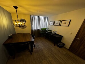 A dining area with a wooden table and chairs, a chandelier, a plant, and a black console table with framed pictures. - Lourdes Executive Suites 201 (Bogotá)