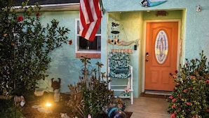 Una casa con un cartel de bienvenida, una bandera y una puerta con un vitral.