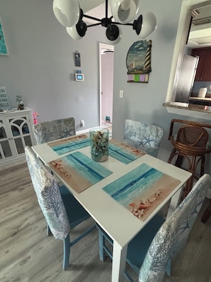 A dining area with a white table, blue chairs, and a ceiling fan.