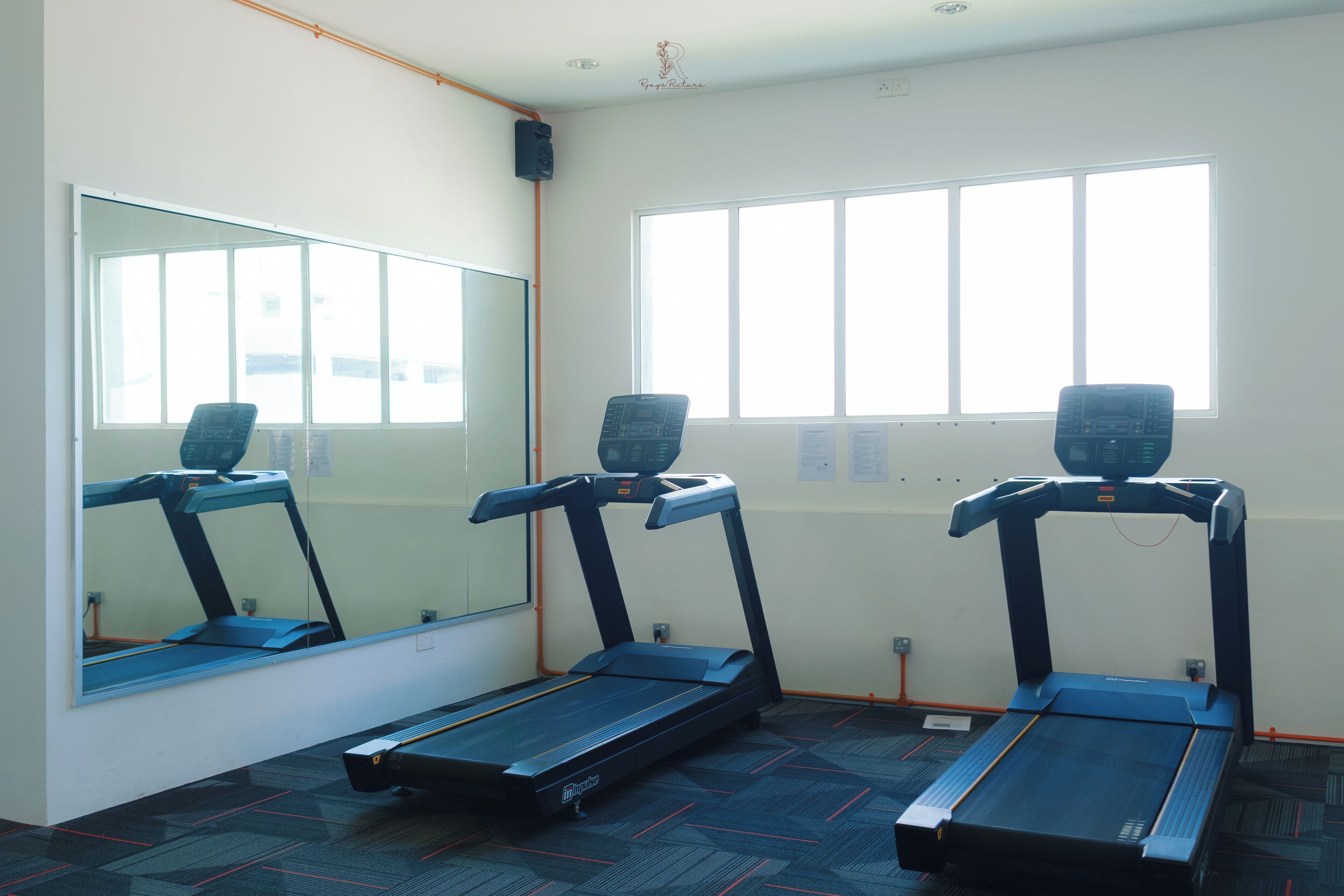 A room with three treadmills, a large mirror, and a window with blinds.