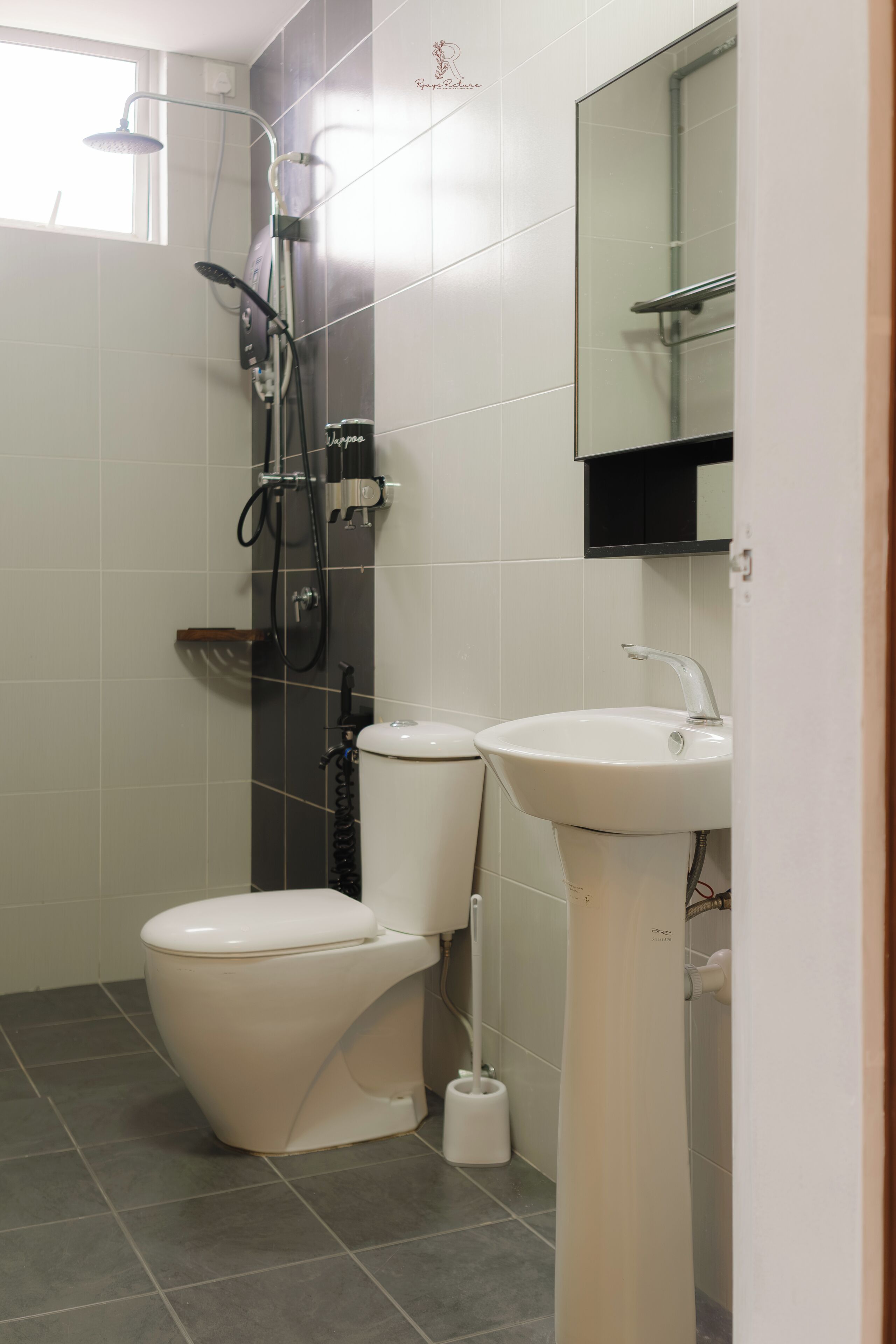 A bathroom with a toilet, sink, shower, and a mirror.