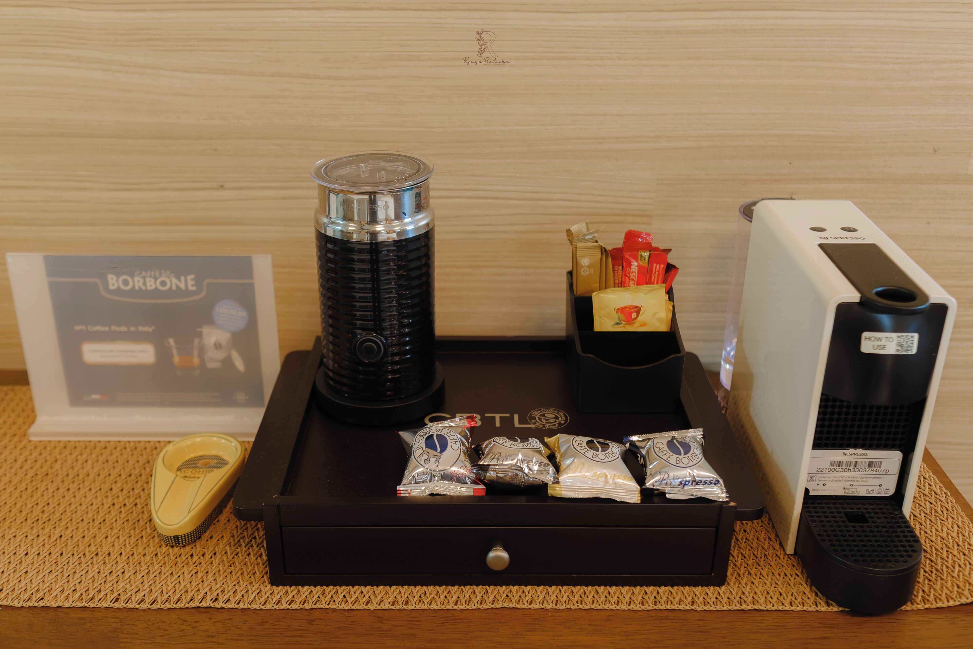 A coffee machine, a coffee pod dispenser, and a coffee pod box on a wooden table.