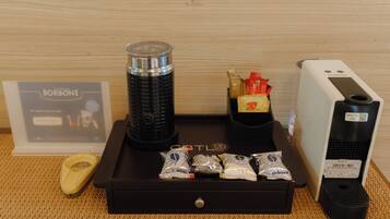 A coffee machine, a coffee pod dispenser, and a coffee pod box on a wooden table.