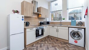 A compact kitchen with a refrigerator, oven, microwave, sink, and washing machine. - Parking Aberdeenshire Retreat Central Peterhead (Aberdeenshire)