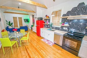 Eine kompakte Küche mit Essbereich, Holzbalken, einem roten Kühlschrank und einer modernen Spritzschutzwand.
