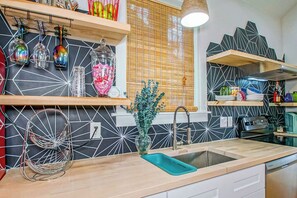 Eine moderne Küche mit schwarz-weißer, geometrischer Spritzschutzwand, Holzböden und verschiedenen Küchengeräten.