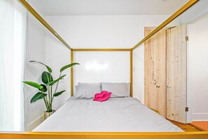Ein Schlafzimmer mit einem Bett, einer Topfpflanze und einer Holztür.
