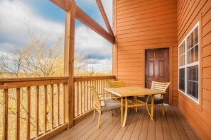 Une terrasse en bois avec une table et des chaises, une porte et une fenêtre.