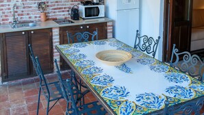 Una cocina con pared de ladrillo, un refrigerador blanco, un microondas y una lámpara colgante.