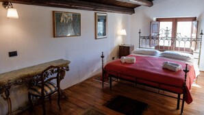 Un dormitorio con cama de madera, un escritorio con silla, una ventana con vistas y un cuadro en la pared.