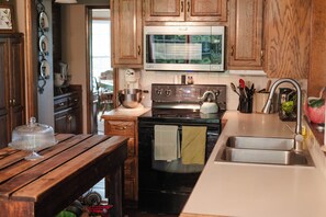 A kitchen with wooden cabinets, a stainless steel sink, a microwave, and a stove. - Private Orchard Estate Near KC - World Cup Stay (Kansas City)
