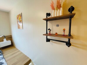 Una habitación con una estantería de madera fijada en la pared, que exhibe objetos decorativos y figuras.