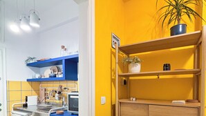 Una cocina con paredes amarillas, estanterías azules y una planta en maceta.