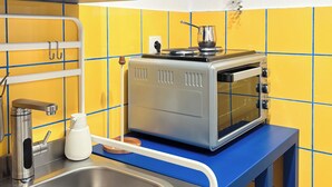 Una cocina con un lavamanos, un tostador y una estantería con utensilios de cocina.