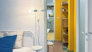 Un dormitorio con cama, mesita de noche, lámpara y vistas al baño, que incluye lavabo y espejo.