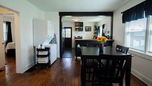 A modern kitchen with a dining area, wooden flooring, and a view of the outdoors. - The Bungalow On Fife only 11 minutes from WEC (Wilmington)