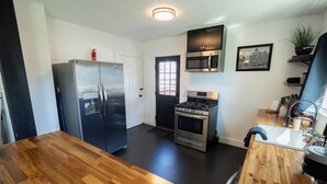 A modern kitchen with stainless steel appliances, a wooden countertop, and a black door. - The Bungalow On Fife only 11 minutes from WEC (Wilmington)