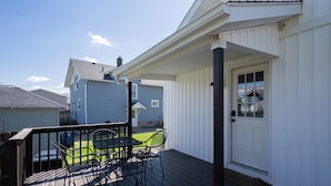A wooden deck with a table and chairs, a white door, and a small garden area. - The Bungalow On Fife only 11 minutes from WEC (Wilmington)