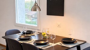 A dining area with a table set for four, black chairs, a blackboard with 'Welcome Home' written on it, and a pendant light above.