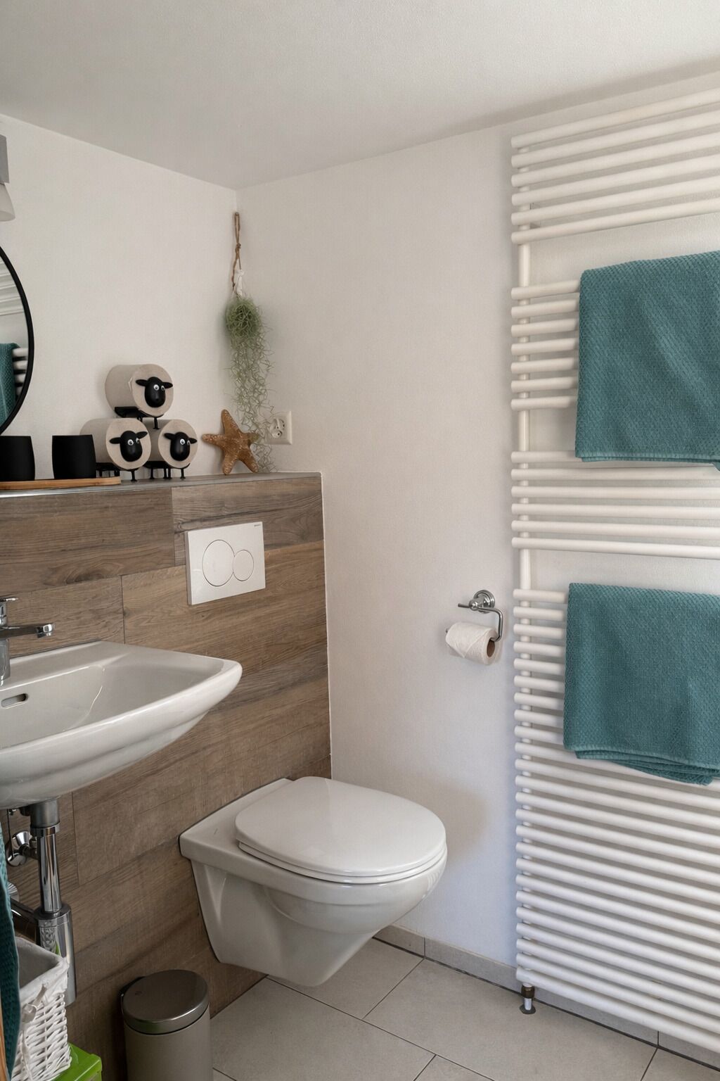 Ein modernes Badezimmer mit einem Holzbadezimmerhocker, einem Waschbecken, einer Toilette und einem Handtuchhalter.